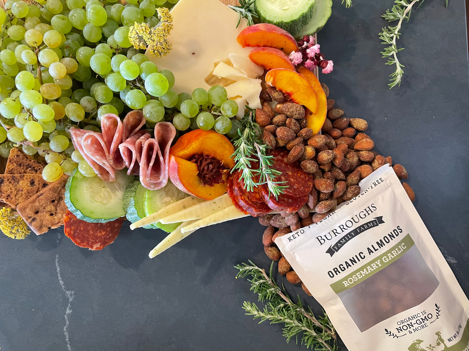 Photo of the Rosemary Garlic almonds spilling out into a beautiful meat, cheese, and fruit board