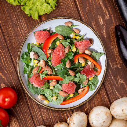 Green salad with grapefruit, peppers and almonds on a wooden table