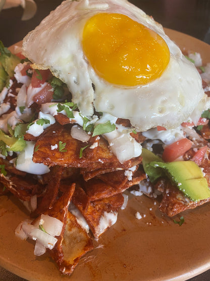 Fried egg over chilaquiles with avocado and salsa