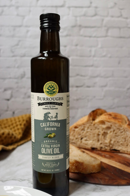 Bottle of Family Blend extra virgin olive oil beside a sliced loaf of bread