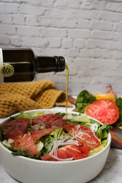 Olive oil being poured over a bowl of grapefruit and greens