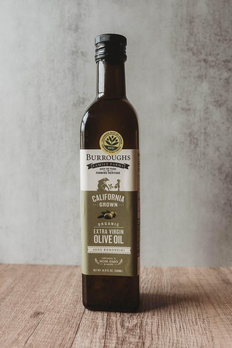 Bottle of Burroughs Family Farms Koroneiki extra virgin olive oil on a wooden surface